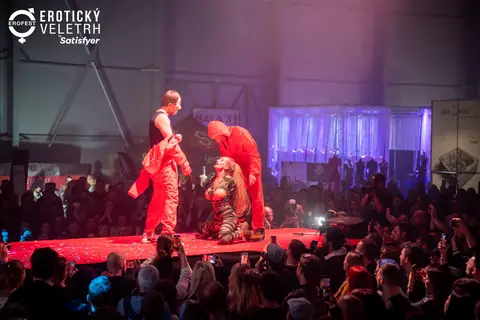 A stage performance in red jumpsuits above a crowd holding up phones, 2022 edition