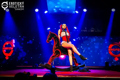 A performer in a corset on a giant rocking horse in the blue-and-red light of the main stage, 2024 edition