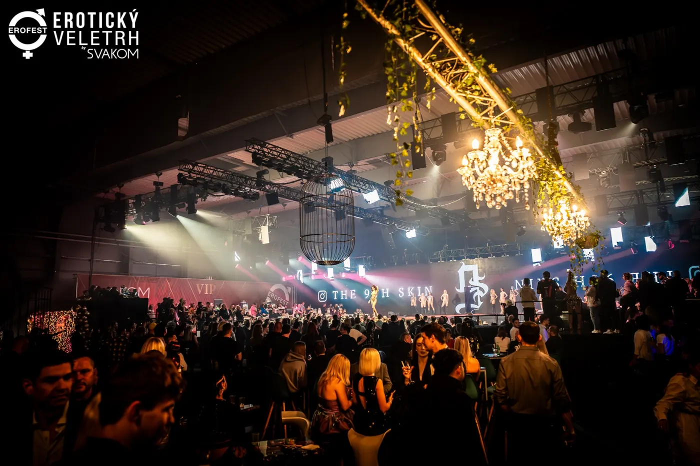 A grandly lit hall with crystal chandeliers above a packed floor