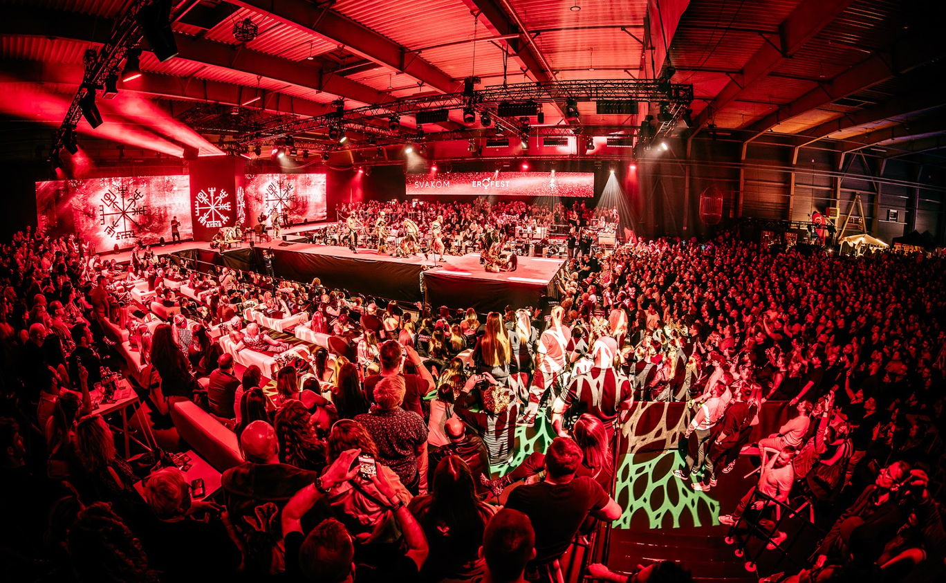 A stripper in a cowboy hat on the main stage among red silhouettes of dancers
