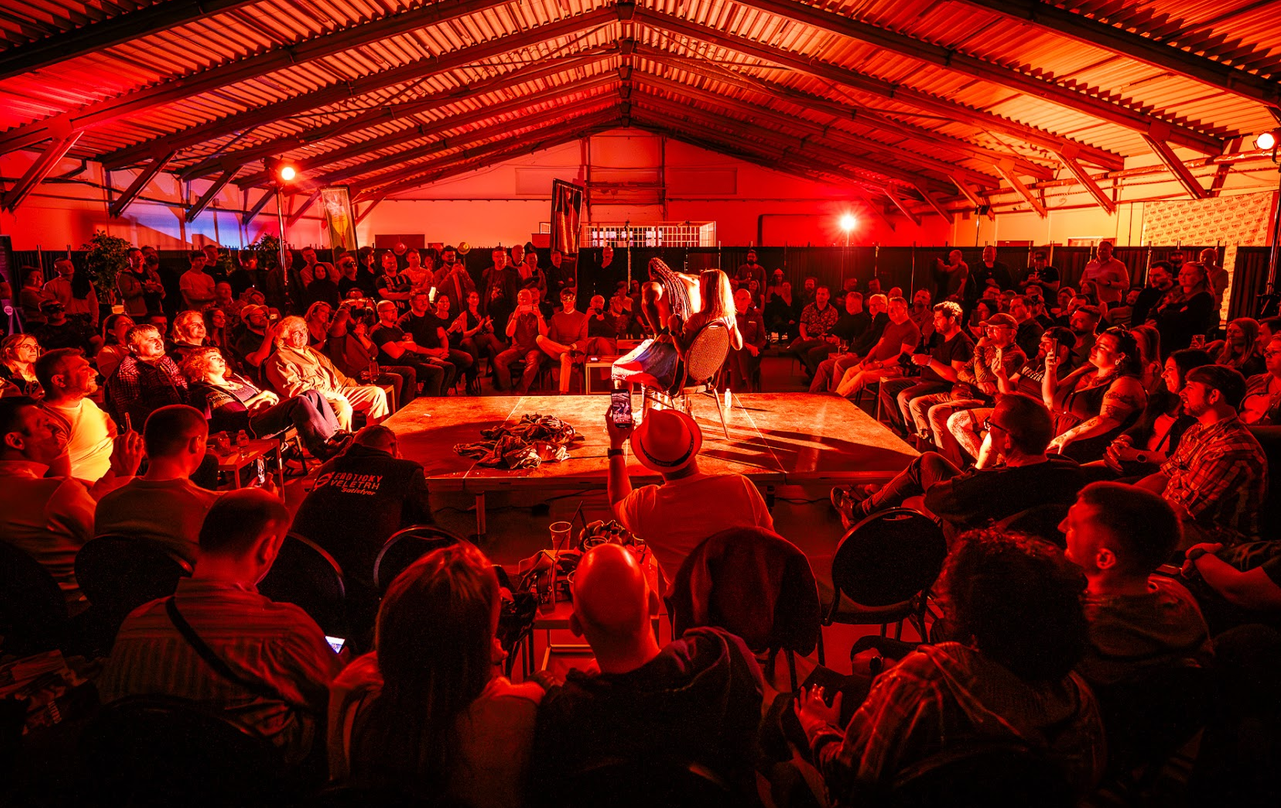 Masked performers mid-show in the dark setting of the Alterno Chambers zone